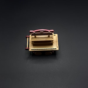 May include: A miniature wooden cart with a red and tan color scheme. The cart has two shelves and four wheels. The top of the cart has a red sign that reads "Candy & Popcorn".