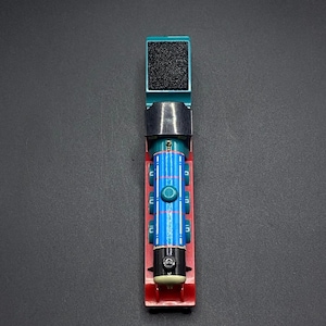 May include: A blue and red toy train engine with a black smokestack and a grey coal car. The train is on a black background.