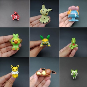 May include: A collection of nine colorful Pokémon figurines. The figurines feature various characters in different poses and colors, including red, green, yellow, and brown. The figures are small and detailed, with distinct features.