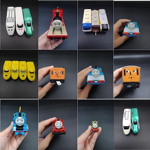 May include: A selection of toy trains in various colours, including red, blue, yellow, and green. The trains feature cartoon faces and are arranged against a dark background. Some trains are held by a hand.