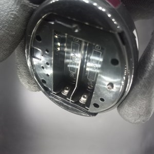 May include: Close-up of the battery compartment of a device, showing two silver battery contacts and the text "1.5V" printed on each battery slot.