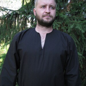 May include: A black long-sleeved shirt with a V-neck and a simple design. The shirt is made of a soft, comfortable fabric.