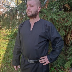 May include: A black long-sleeved shirt with a V-neck and a leather belt. The shirt is made of a soft, comfortable fabric and has a relaxed fit.