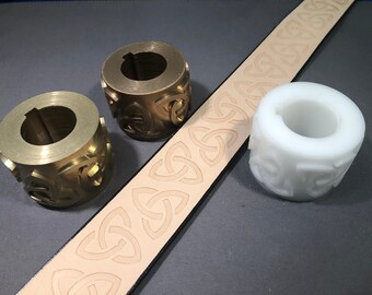 May include: Two brass and one white plastic stamp rollers with a Celtic knot design. The rollers are used to create a repeating pattern on leather.