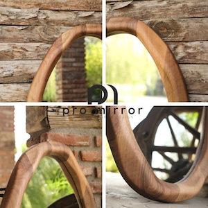 May include: A wooden oval mirror with a unique, organic shape. The frame is made of natural wood with a rich brown colour and a smooth finish. The mirror is perfect for adding a touch of nature to any room.