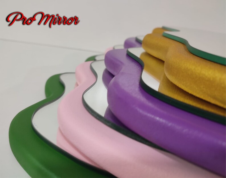 May include: A set of five wavy-edged mirrors with different colored frames. The frames are green, pink, purple, gold, and green. The mirrors are stacked on top of each other.