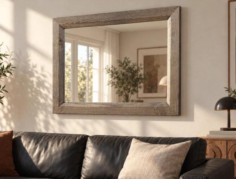 Peut inclure: Un miroir mural rectangulaire dot&eacute; d'un cadre &eacute;pais en bois gris patin&eacute; avec une texture de grain visible. La vitre du miroir refl&egrave;te un espace int&eacute;rieur lumineux avec une fen&ecirc;tre, une plante en pot et un cadre au mur.