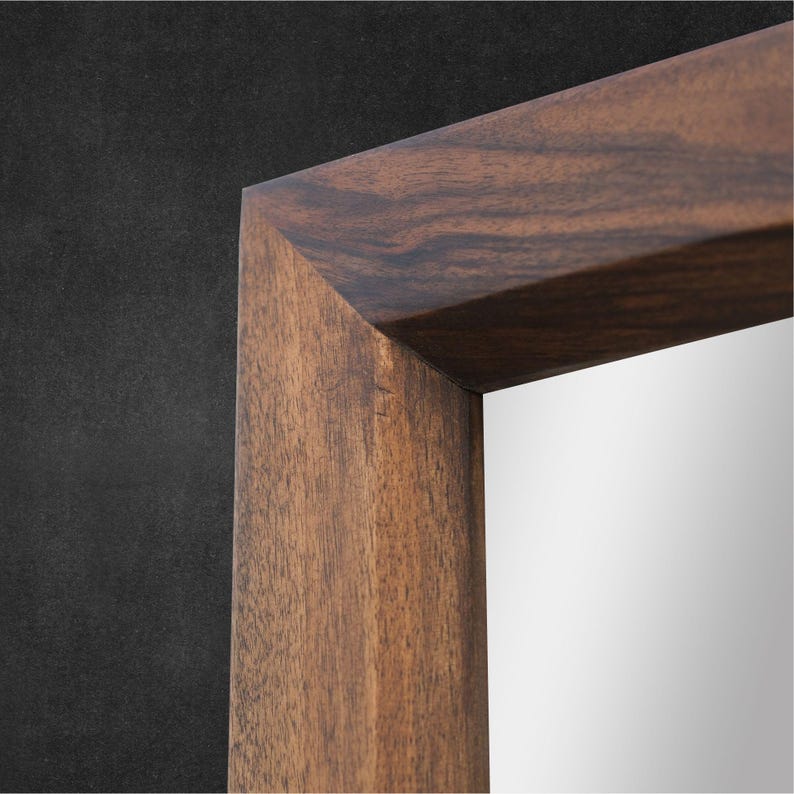 Peut inclure: Un miroir rectangulaire dot&eacute; d'un cadre &eacute;pais en bois brun fonc&eacute; avec un motif de grain naturel visible. Le cadre pr&eacute;sente des coins en onglet nets et pr&eacute;cis ainsi qu'une finition lisse, entourant une surface en verre r&eacute;fl&eacute;chissante.