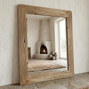 May include: A rectangular mirror with a natural wood frame. The frame has a rustic, weathered appearance with visible grain and knots. The mirror reflects a room with a fireplace, rug, and vases, creating a warm, inviting ambiance.