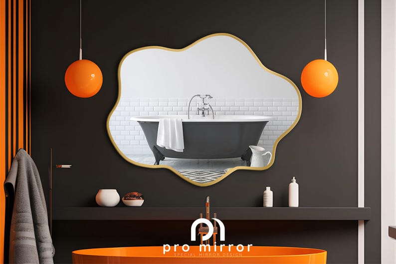 May include: A gold-framed, irregular-shaped mirror reflects a black bathtub with white tile walls. Two orange globe pendant lights hang above the mirror. The mirror is labeled "pro mirror special mirror design".