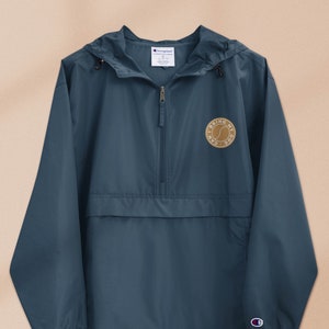 May include: A navy blue windbreaker jacket with a zipper closure and a drawstring hood. The jacket has a small embroidered patch on the left chest that says "I BRING MY DOG".