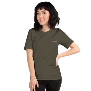 May include: A woman wearing a dark green short-sleeved t-shirt with the text "dog mom" in white lettering.