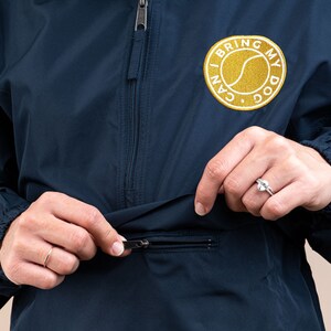 May include: A navy blue windbreaker jacket with a zipper closure and a gold embroidered patch that says "I Can Bring My Dog".