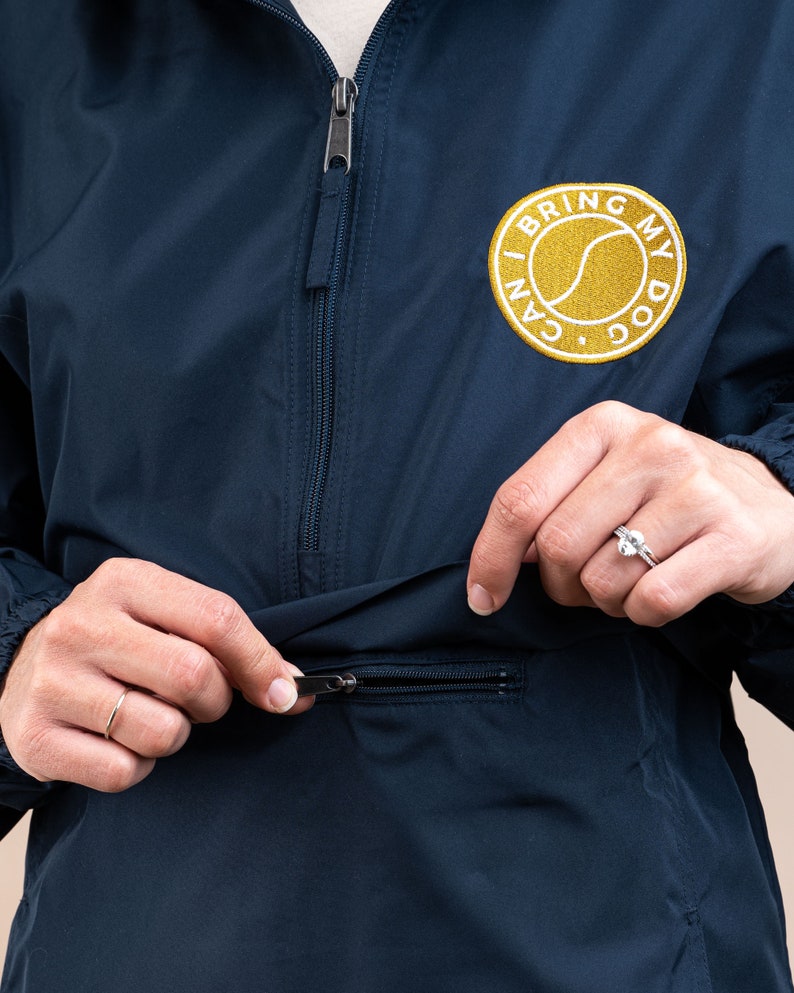 May include: A navy blue windbreaker jacket with a zipper closure and a gold embroidered patch that says "I Can Bring My Dog".