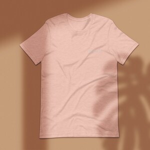 May include: A light pink t-shirt with the text "dream big" printed on the front in a white font.