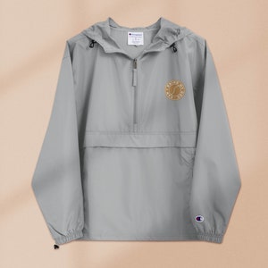 May include: A gray hooded windbreaker with a zipper closure and a small embroidered logo on the left chest that says "Bring My A-Game".