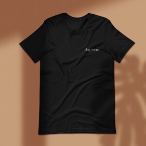 May include: Black t-shirt with the text "dog mom" printed in white on the front.