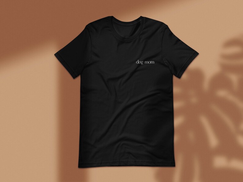 May include: Black t-shirt with the text "dog mom" printed in white on the front.