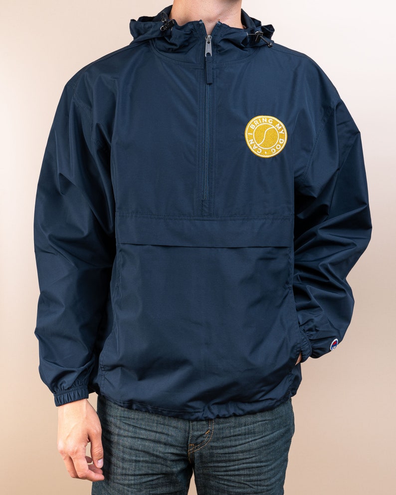May include: A navy blue windbreaker jacket with a zipper closure and a hood. The jacket has a yellow embroidered patch on the left chest that says "I Can Bring My Dog".