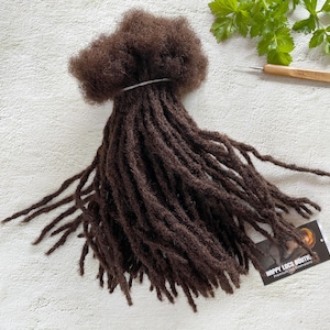 Può includere: Un pacchetto di dreadlock di capelli umani castano scuro. Le dreadlock sono legate insieme con un elastico. Le dreadlock sono lunghe circa 50 cm.