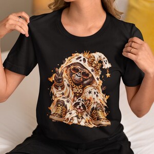 Könnte beinhalten: Ein schwarzes T-Shirt mit einem Grafikdruck eines Gorillas und eines kleinen Hundes, die geisterartige Kapuzenumhänge mit Leopardenmuster tragen. Der Gorilla trägt eine Sonnenbrille und eine goldene Kette mit dem Schriftzug BOO.