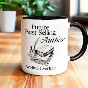 May include: White ceramic mug with a black rim and handle. The mug has a black and white illustration of a stack of books, a pen, and a glass of water. The text "Future Best-Selling Author" is printed in black on the mug. The name "Aveline Everhart" is printed in black at the bottom of the mug.