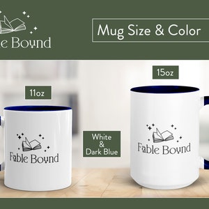 May include: Two white ceramic mugs with a dark blue rim and handle. The mugs feature a black and white illustration of an open book with stars. The text "Fable Bound" is printed on the mugs. The mugs are available in 11oz and 15oz sizes.