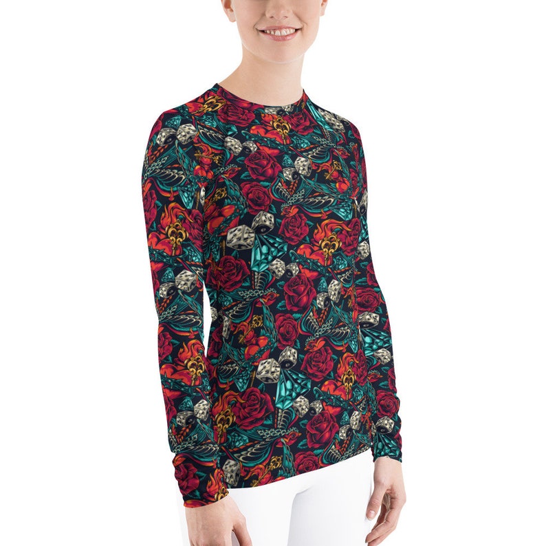 May include: A long-sleeved shirt with a colorful pattern featuring roses, dice, and other designs. The shirt is black with red, blue, and green accents.