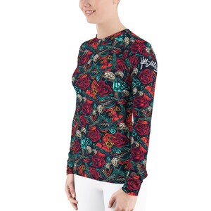May include: A long-sleeved shirt with a dark blue background and a colorful pattern of roses, skulls, and other designs. The text "Juggalo" is printed on the right sleeve.