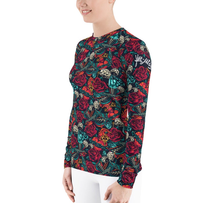 May include: A long-sleeved shirt with a dark blue background and a colorful pattern of roses, skulls, and other designs. The text "Juggalo" is printed on the right sleeve.