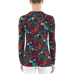 May include: A long-sleeved shirt with a colorful pattern of roses, dice, and other designs. The shirt is black with red, blue, and green accents.