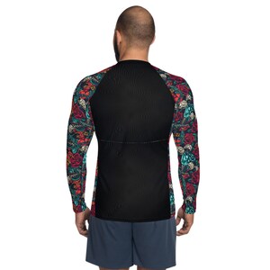 Puede incluir: Camiseta negra de manga larga con estampado floral y calavera de colores en las mangas. La camiseta tiene un fondo negro y un sutil patr&oacute;n texturizado.
