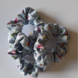 May include: Two blue scrunchies with a white and colourful bird and leaf pattern.