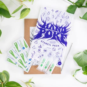 May include: A stencil pack with a blue and white design, accompanied by sterile alcohol prep pads and applicators. The pack includes the text "HAND POKE STENCIL PACK" and various symbols. Green and white packaging is visible.