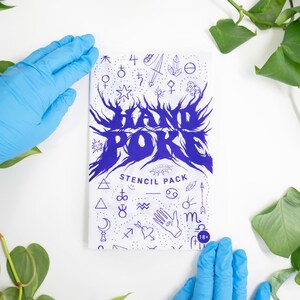 May include: A white stencil pack with blue text and illustrations, including the words "HAND POKE" in a stylized font. The pack features various symbols and is surrounded by green plants and blue gloved hands.