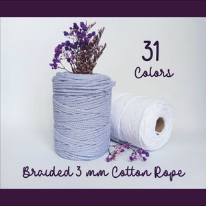 May include: Two spools of 3 mm braided cotton rope, one in light purple and one in white. The text "31 Colors" is written above the spools. The text "Braided 3 mm Cotton Rope" is written below the spools.