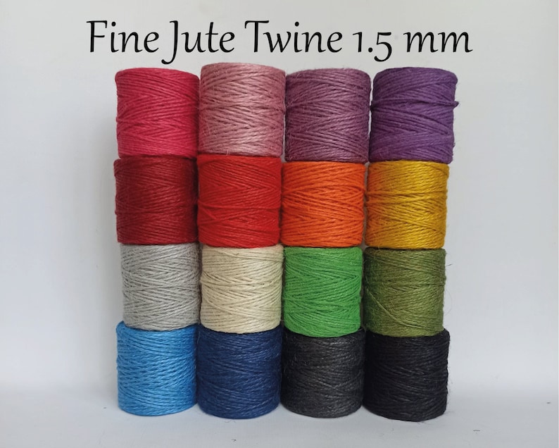 Op de afbeelding: Spoelen fijn jute touw in diverse kleuren, waaronder rood, roze, paars, oranje en groen. De tekst "Fine Jute Twine 1.5 mm" staat bovenaan. Het touw is strak opgerold en klaar voor knutselen of andere toepassingen.