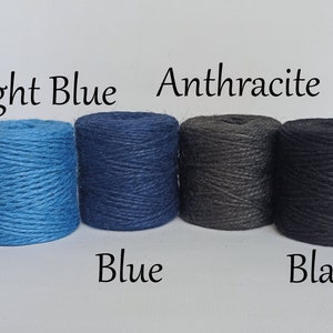 Op de afbeelding: Vier strengen touw in lichtblauw, blauw, antraciet en zwart. De kleuren zijn gelabeld met de bijbehorende kleurnamen. Het touw is strak opgerold in cilindrische vormen, ideaal voor knutselen of decoratieve doeleinden.