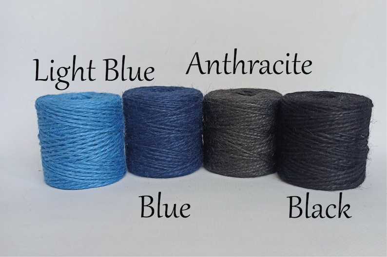 Op de afbeelding: Vier strengen touw in lichtblauw, blauw, antraciet en zwart. De kleuren zijn gelabeld met de bijbehorende kleurnamen. Het touw is strak opgerold in cilindrische vormen, ideaal voor knutselen of decoratieve doeleinden.