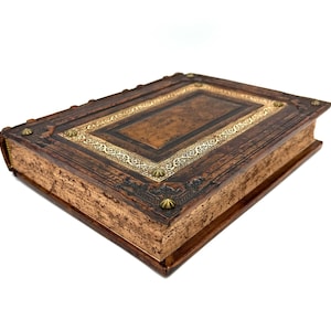 May include: A brown leather-bound journal with gold accents and decorative metal studs. The journal has a worn, vintage look.