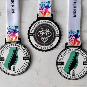 Puede incluir: Tres medallas en blanco y negro con diseños diferentes. La medalla superior presenta una bicicleta y el texto "Manhattan Perimeter Run" con las fechas "Nov 17" y "2024". La medalla del medio presenta un mapa de Manhattan y el texto "Manhattan Perimeter Run" con las fechas "Nov 17" y "2024". La medalla inferior presenta un mapa de Manhattan y el texto "Manhattan Perimeter Run" con las fechas "Nov 17" y "2024".