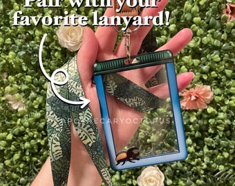 May include: A clear ID badge holder with a blue border and a green lanyard with a leaf pattern. The text "Pair with your favorite lanyard!" is displayed above the holder. The badge holder has a small beetle graphic.
