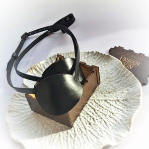May include: A black leather eye patch with an adjustable strap. The eye patch is in a small wooden box with the text "URBAN SKIN" on the lid.