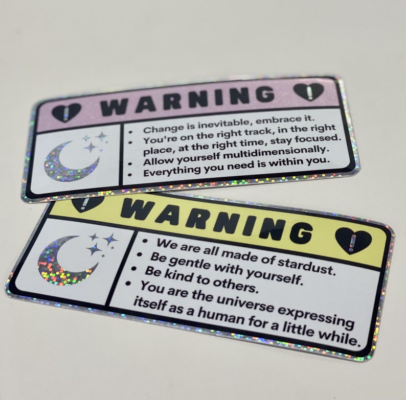 Puede incluir: Dos pegatinas de advertencia con un dise&ntilde;o de luna creciente y estrellas. La primera pegatina es rosa con el texto "El cambio es inevitable, ac&eacute;ptalo. Est&aacute;s en el camino correcto, en el lugar correcto, en el momento correcto, mantente concentrado. Perm&iacute;tete ser multidimensional. Todo lo que necesitas est&aacute; dentro de ti." La segunda pegatina es amarilla con el texto "Todos estamos hechos de polvo de estrellas. S&eacute; amable contigo mismo. S&eacute; amable con los dem&aacute;s. T&uacute; eres el universo que se expresa como un humano por un tiempo."