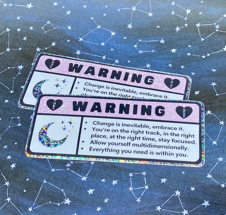 Puede incluir: Dos pegatinas de advertencia rosa y blancas con un dise&ntilde;o de luna creciente y estrellas. El texto en las pegatinas dice "ADVERTENCIA" e incluye el siguiente mensaje: "El cambio es inevitable, ac&eacute;ptalo. Est&aacute;s en el camino correcto, en el lugar correcto, en el momento correcto, mantente concentrado. Perm&iacute;tete ser multidimensional. Todo lo que necesitas est&aacute; dentro de ti."