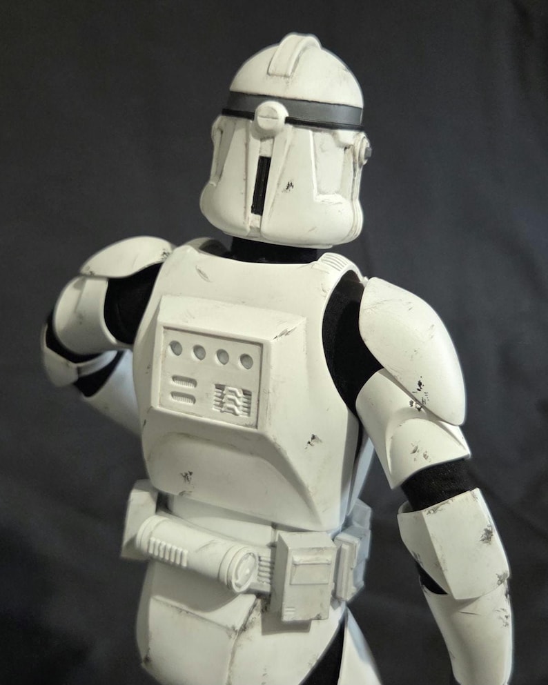 May include: A white action figure of a clone trooper from a science fiction franchise. The figure is wearing white armor with black accents and a helmet. The figure is posed with its back to the viewer.