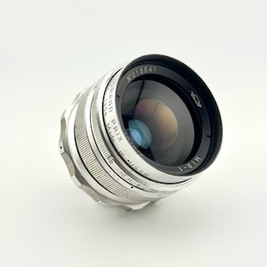 May include: A vintage silver MIR-1 camera lens, made in USSR, with the text "GRAND PRIX 1958" and serial number N°018641. The lens has a black front element and a series of aperture settings.