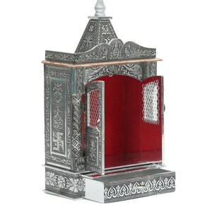 May include: A silver metal temple with intricate carvings and a red interior. The temple has a drawer at the bottom and a small door that opens to reveal the interior.