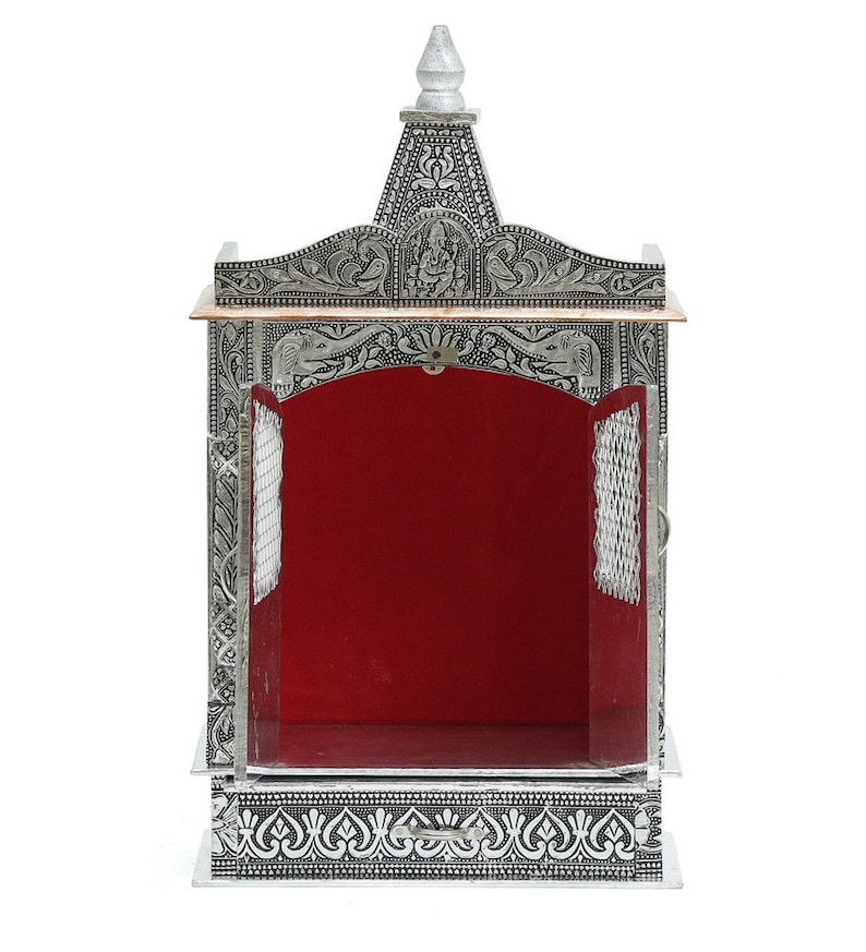 May include: A silver and copper-toned metal temple with intricate floral and geometric designs. The temple has a red velvet interior and a small, pointed roof.