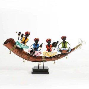 Pode incluir: Uma escultura de metal de cinco músicos tocando instrumentos em um chifre curvo de cor cobre. Os músicos são pintados em cores brilhantes, incluindo vermelho, amarelo, azul, verde e branco. A escultura está sobre uma base preta.